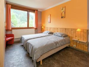 マルメディにあるAppealing holiday home in Malm dy with indoor poolのオレンジ色の壁と窓が備わる客室で、ベッド2台が付いています。