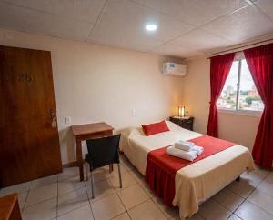 a bedroom with a bed and a desk and a window at Apart Hotel Belgrano in Perico