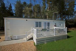a white tiny house with a porch and stairs at 7. Supreme OD 3 Caravan with Decking in Ringwood
