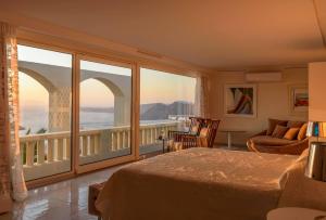 a bedroom with a bed and a balcony with a view at Santorini Gem in Órmos Athiniós