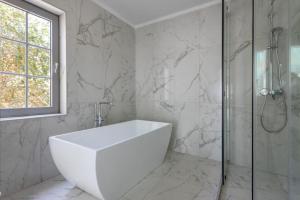 a white bathroom with a tub and a shower at Santorini Gem in Órmos Athiniós +34 photos