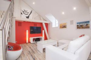 a living room with white furniture and a red wall at AppartCosy 04 in Vitré
