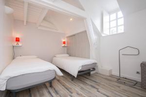two beds in a room with white walls and a window at AppartCosy 04 in Vitré