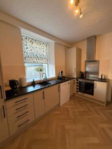 a kitchen with white cabinets and a sink and a window at Home in Macduff in Macduff