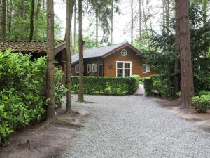 uma casa na floresta com uma entrada de cascalho em Luxurious Chalet in Oud Turnhout with Large Garden em Oud-Turnhout