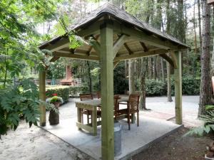 a wooden gazebo with a table and chairs at Luxurious Chalet in Oud Turnhout with Large Garden in Oud-Turnhout