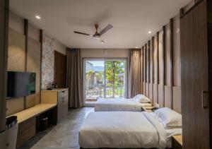 a hotel room with two beds and a television at Vanasya Retreat Corbett in Amgarhi +23 photos