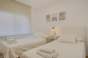 two beds in a white room with towels on them at Molí de Mar - Smart Hotel in Lloret de Mar