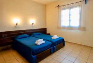 a room with two blue beds and a window at Mandilada Family Village - Seaview Villas in Marathokampos