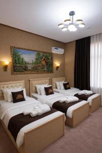 a hotel room with four beds and a painting on the wall at GRAND CARAVAN in Tashkent