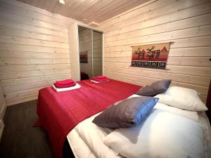 a bedroom with a bed with a red blanket and pillows at Lumilyhty A in Äkäslompolo