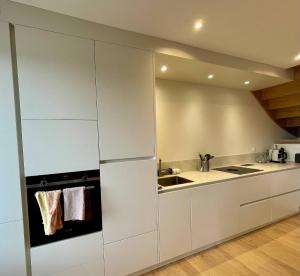 a kitchen with white cabinets and a sink at AppartCosy 10 in Vitré