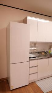 a kitchen with white cabinets and a white refrigerator at yua sugar home in Daegu