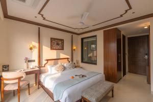 a bedroom with a bed and a desk and a chair at Luxuria Varanasi By Moustache in Varanasi