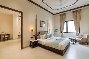 a bedroom with a large bed and a living room at Luxuria Varanasi By Moustache in Varanasi