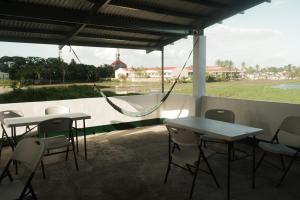a porch with two tables and chairs and a hammock at Tukad Guest House in Sampong