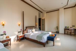 a bedroom with a large bed and a table at Luxuria Varanasi By Moustache in Varanasi