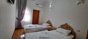 a room with two beds and a window at Hotel Naqsh-band Terrace in Bukhara +76 photos