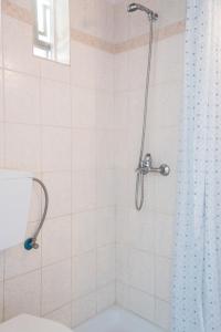 a bathroom with a shower with a blue shower curtain at Fardini Seaside Hotel in Kavos +6 photos