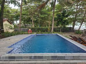 a swimming pool with blue water in a yard at Kambuna Bungalow in Krui