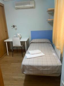 a bedroom with a bed and a table and a chair at REMANAL Residencia in Salamanca