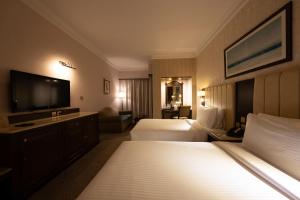 a hotel room with two beds and a flat screen tv at Luxe Avenue Hotel in Dubai