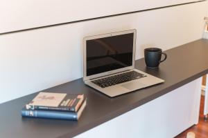 a laptop computer sitting on a desk with a cup and books at Santi Cabodeiro in Isla de Arosa
