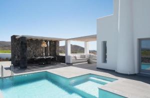a villa with a swimming pool and a patio at La Ponta Villas & Suites in Akrotiri
