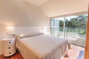 a white bedroom with a bed and a large window at Santi Cabodeiro in Isla de Arosa +34 photos