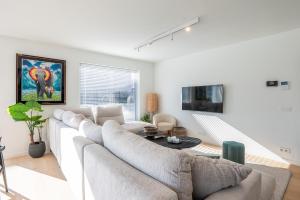 a white living room with a large couch and a table at Luxury Apartment with 4 Rooms, Pool and Modern Comfort in De Haan