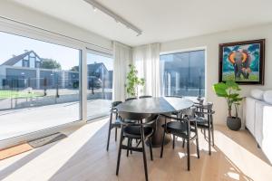 a dining room with a table and chairs and a large window at Luxury Apartment with 4 Rooms, Pool and Modern Comfort in De Haan
