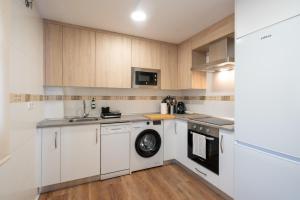 a kitchen with white cabinets and a washing machine at Apartamentos GO - Simancas in Simancas