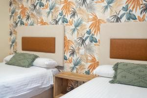two beds in a room with floral wallpaper at Apartamentos GO - Simancas in Simancas