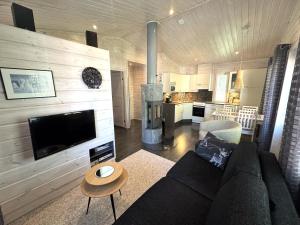a living room with a couch and a tv and a kitchen at Lumilyhty A in Äkäslompolo