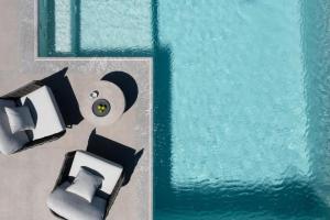 a view of a pool with a bed and a chair at La Ponta Villas & Suites in Akrotiri +54 photos
