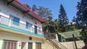 a white building with a staircase next to a tree at vishranti homestayy in Rishīkesh