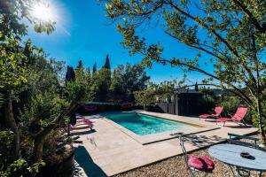 a swimming pool in a backyard with pink chairs around it at Le Roc sur l'Orbieu in Saint-Pierre-des-Champs
