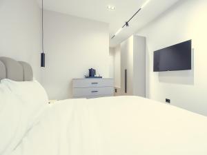 a white bedroom with a bed and a tv at Enigma Rooms in Lezhë +21 photos
