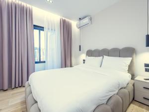 a bedroom with a large white bed and a window at Enigma Rooms in Lezhë