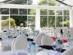 a room with white tables and chairs and windows at Ulifalodge whitehouse in Hillcrest