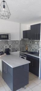 a kitchen with a white counter top and black cabinets at Studio cabine à proximité des plages in Gruissan