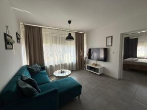 a living room with a blue couch and a television at Apartman "WALKOW", SELF CHECK IN, FREE PARKING in Vukovar