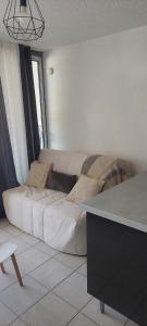 a living room with a large white couch in a room at Studio cabine à proximité des plages in Gruissan
