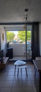 a living room with a table and a window at Studio cabine à proximité des plages in Gruissan