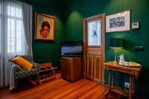 a living room with green walls and a chair and a television at Casa Inquieta Hotel Boutique in Seville