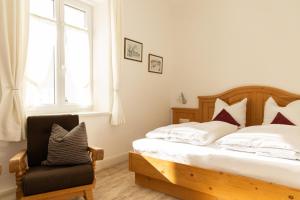 a bedroom with a bed and a chair and a window at Ferienwohnungen Ruasers Ruah in Mittenwald