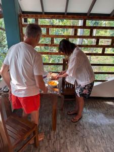 a man and a woman standing at a table with a bowl of food at French Villa in Dankotuwa