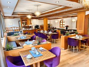 a restaurant with wooden tables and purple chairs at Stadthotel Münze in Bad Mergentheim