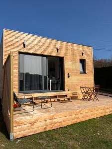 a tiny house with a deck with a table and chairs at Sof tiny in Moyenmoutier