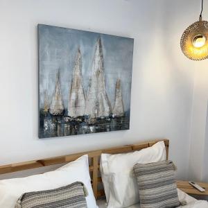 a painting hanging above a bed with white pillows at The Minimal Apartments 3Floors in Loutra Edipsou